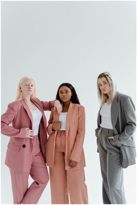 Three diverse women in elegant blazers posing conf
