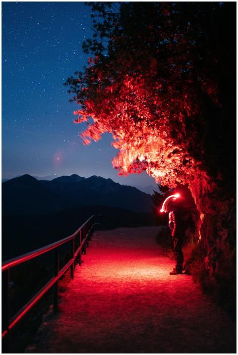 A lone hiker with a red light walking on a mountai