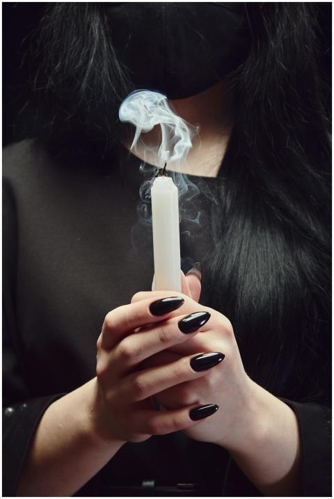 Close-up of hands holding a candle with smoke agai