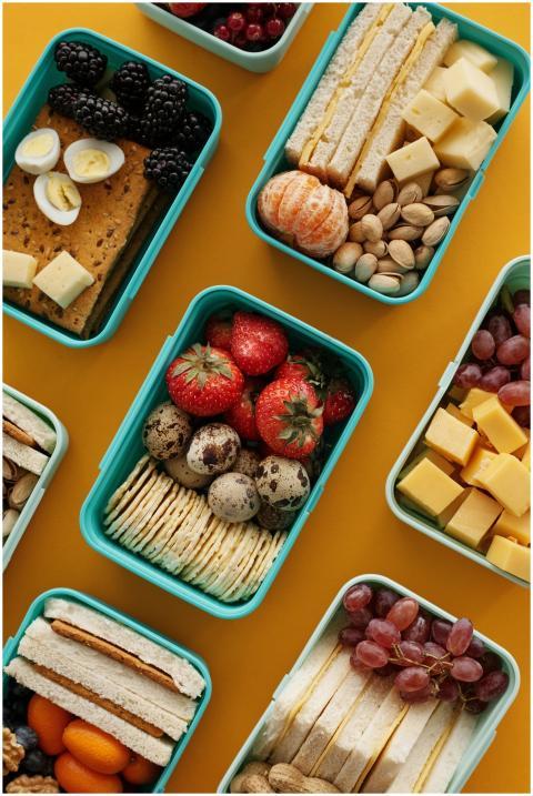 Top view of diverse snacks in bento boxes on yello