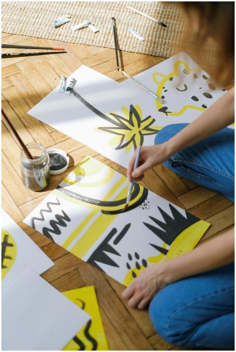 A person painting abstract designs on paper in a b