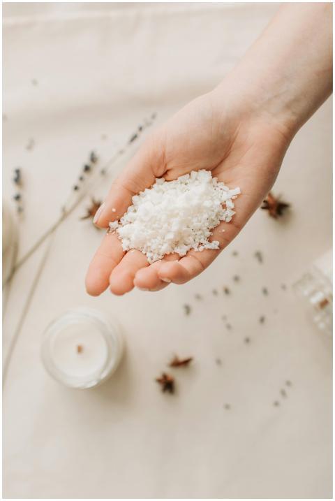 Hand holding natural bath salts with candle, promo