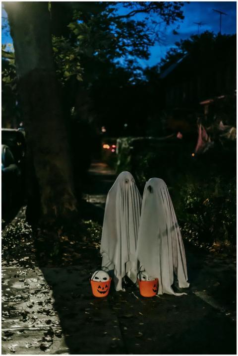 Two children dressed as ghosts with Halloween buck