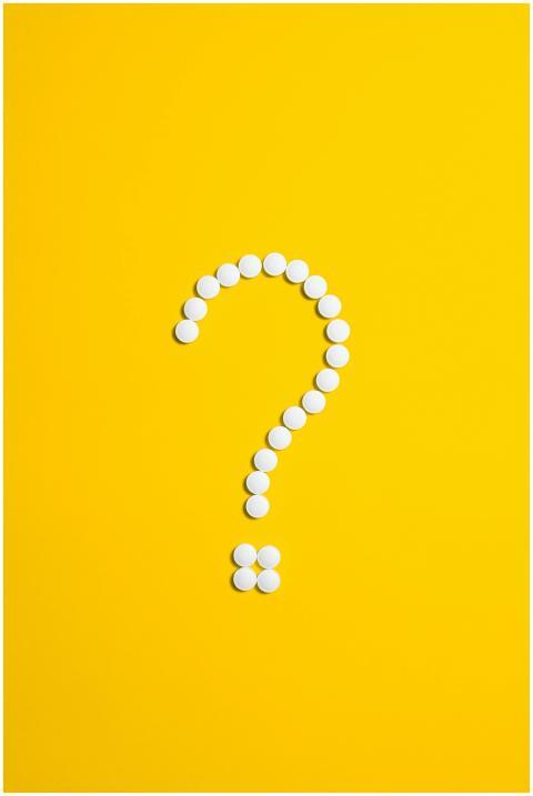 White pills arranged in a question mark shape on a