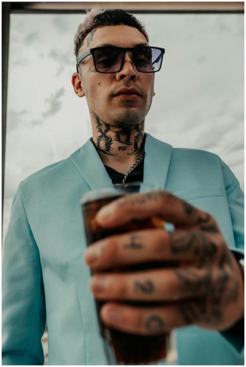 Close-up of a fashionable man with tattoos holding