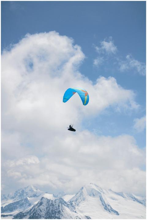 Paraglider flying high above the snowy Alps with a