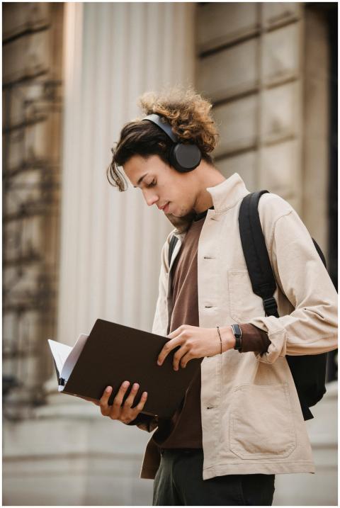 A young adult wearing headphones studies from a fo
