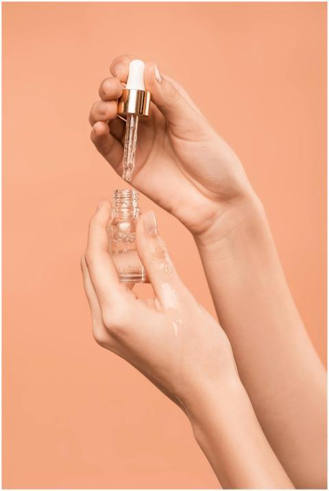 Close-up of hands using a dropper to apply skincar