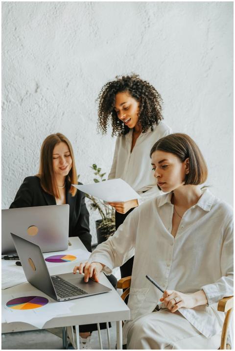 Three diverse businesswomen collaborating around l