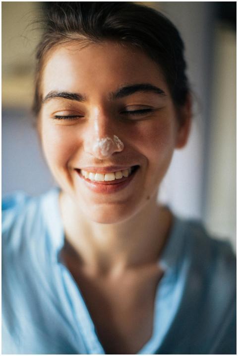 Close-up portrait of a smiling woman with cream on