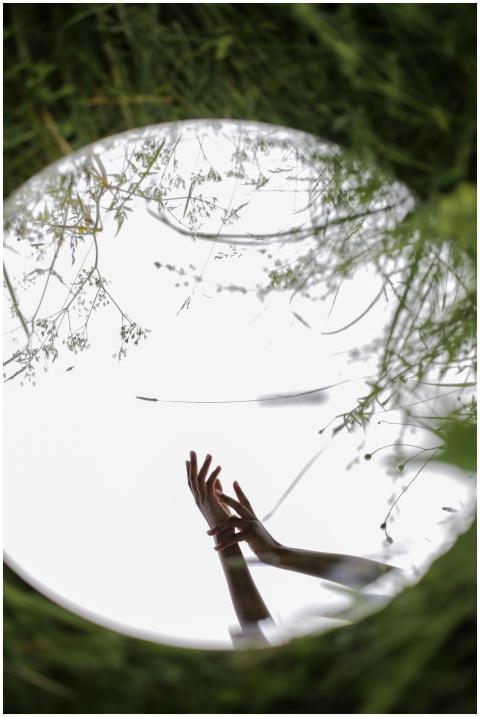 Reflective mirror in nature with hands creating a