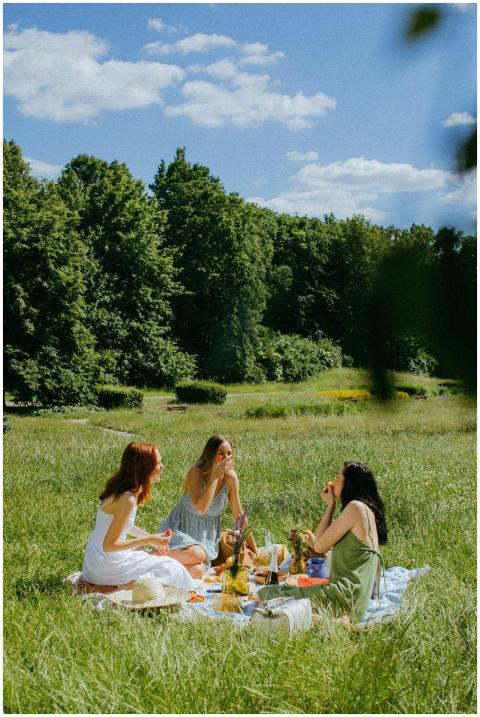 Three women enjoy a serene picnic in a sunny park