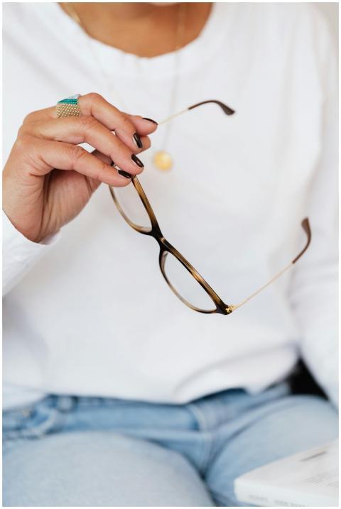 Close-up of a woman holding eyeglasses, suggesting