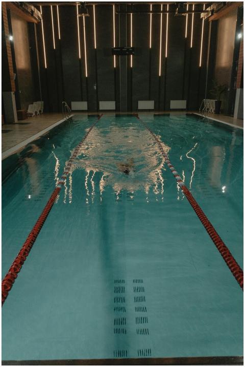 An unrecognizable swimmer glides through an indoor