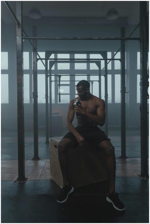 Shirtless man sitting in gym, resting after workou