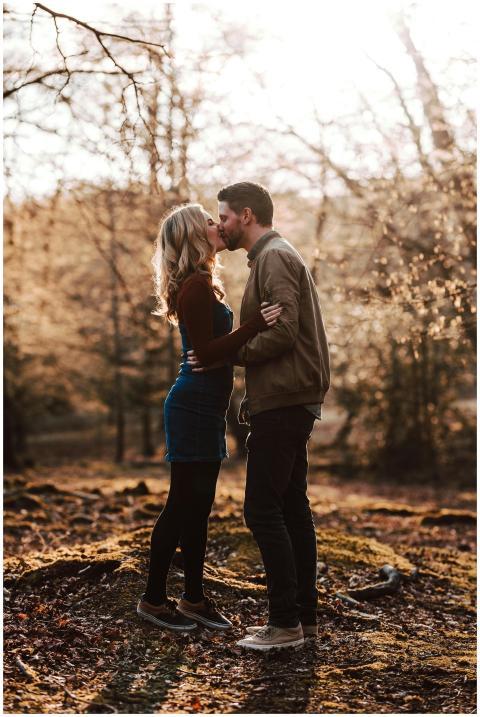 A couple shares a romantic kiss in an autumn fores
