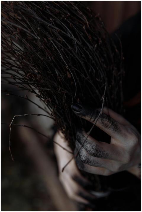 Close-up of a witch's hand clutching a broom, evok