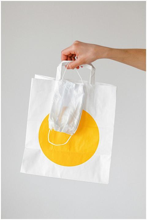 Close-up of a hand holding a paper shopping bag wi