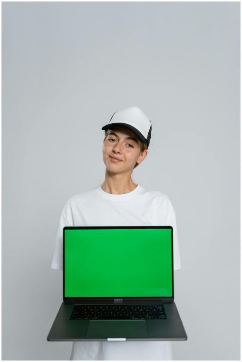 Young woman with cap holding a green screen laptop