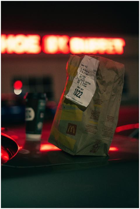 A McDonald's paper bag on a car roof at night with