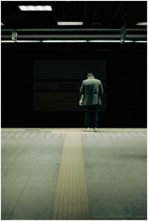 Man in jacket standing on metro platform, awaiting