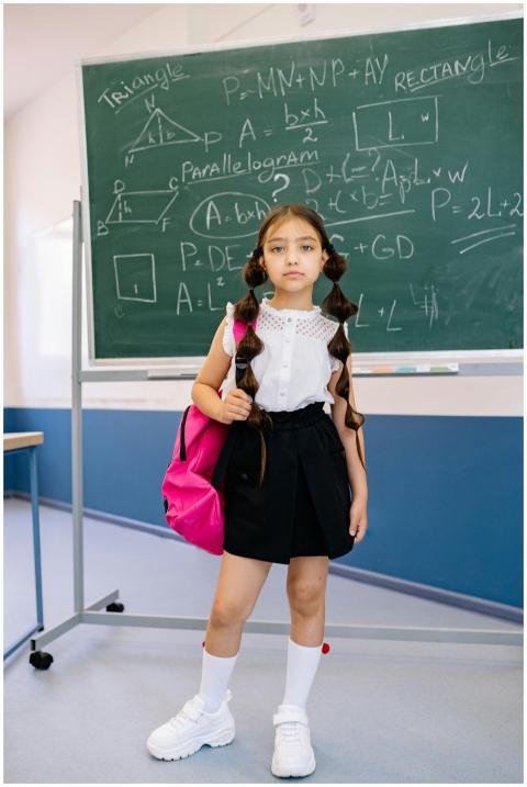 A young girl with a backpack stands confidently in