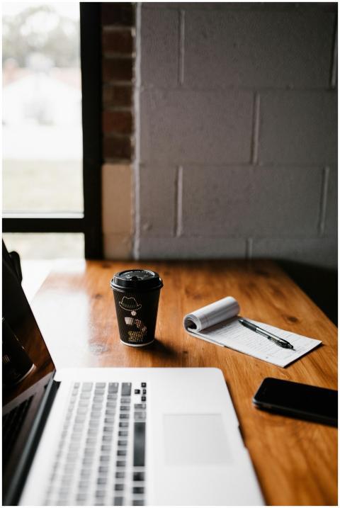 A cozy workspace featuring a laptop, coffee cup, n
