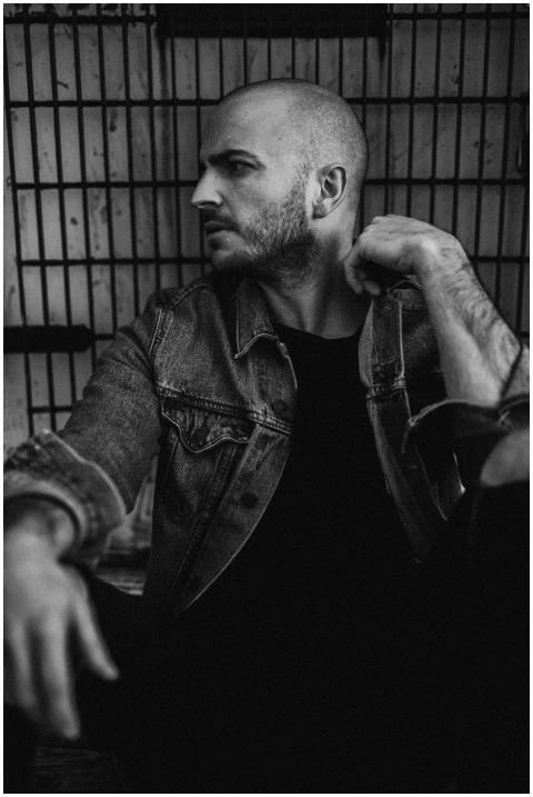 Grayscale portrait of a bald man in a denim jacket