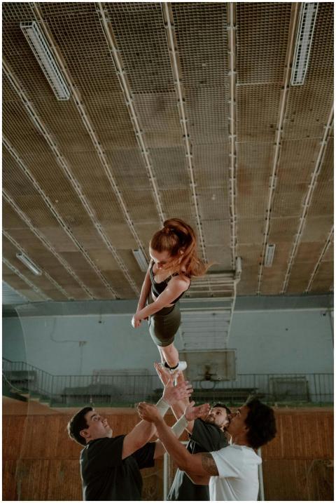 Group practicing a cheerleading stunt indoors with