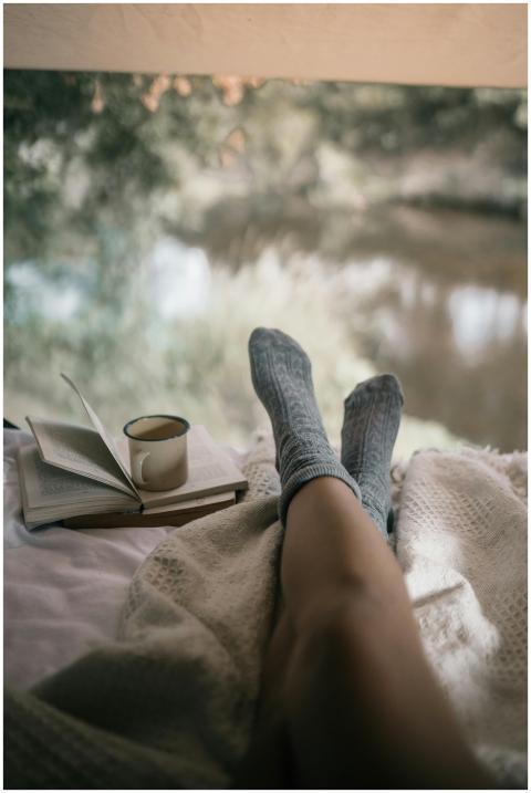 Woman relaxing with socks, book, and coffee by win