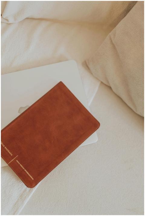 Brown leather Bible resting on a closed laptop on