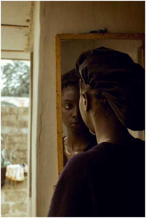 Woman in a black beret reflects in a vintage mirro