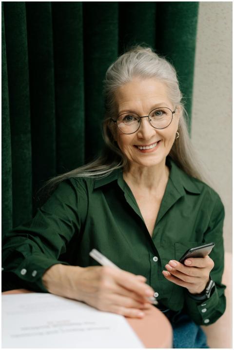Smiling senior woman with gray hair and glasses ho