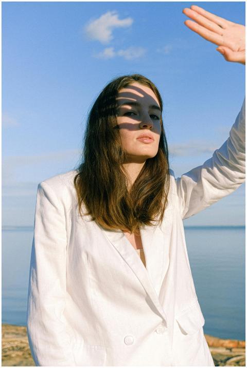 Stylish woman in a white blazer shielding her eyes