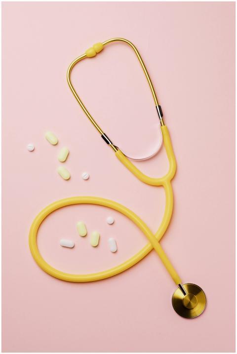 Flat lay of a yellow stethoscope and assorted pill