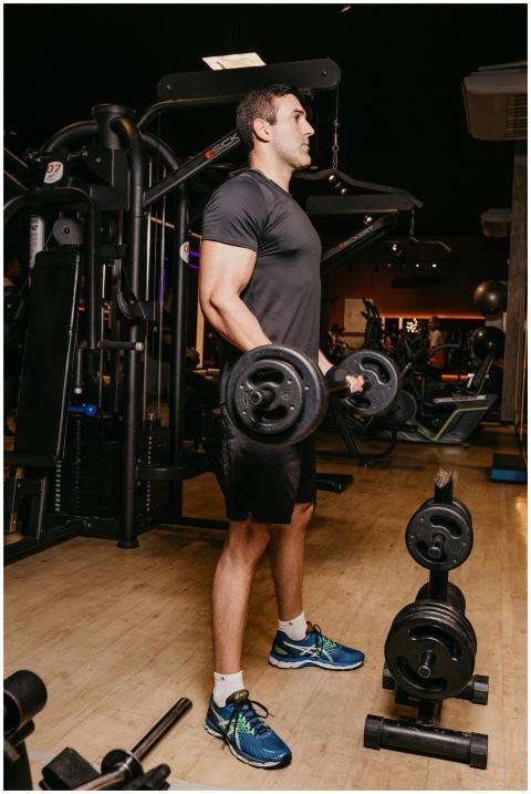 Fit adult man in gym performing weightlifting work