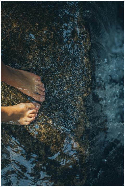 A calming scene of bare feet on a wet rock with fl