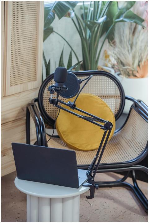 Modern laptop and microphone on tripod placed near