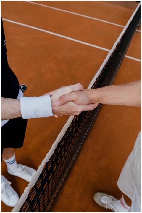 Two tennis players in a friendly handshake over a