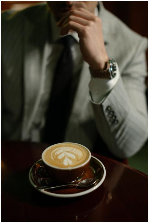 A stylish man in a suit enjoys a latte with art in