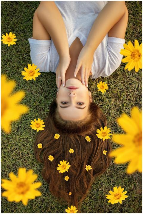 Upside down portrait of a woman lying on grass wit