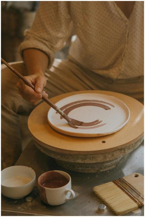 A craftsman skillfully paints a ceramic plate in a