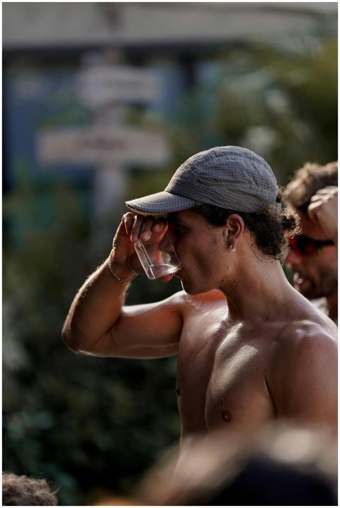 A shirtless young man drinks water during an outdo