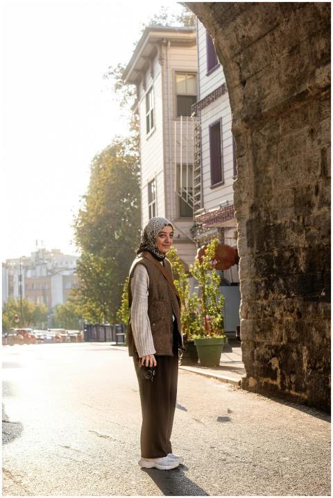 A woman in casual attire stands by a historic ston