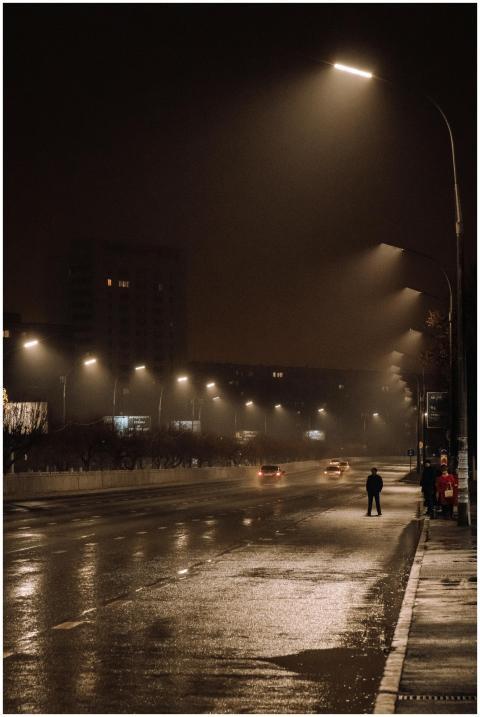 A quiet city street at night with rain-soaked asph