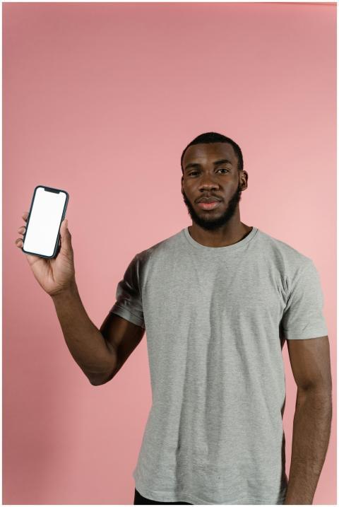 Black man in gray shirt holding a smartphone on a