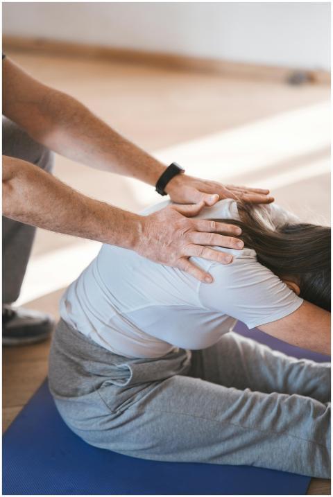 Person stretching on a yoga mat with assistance in