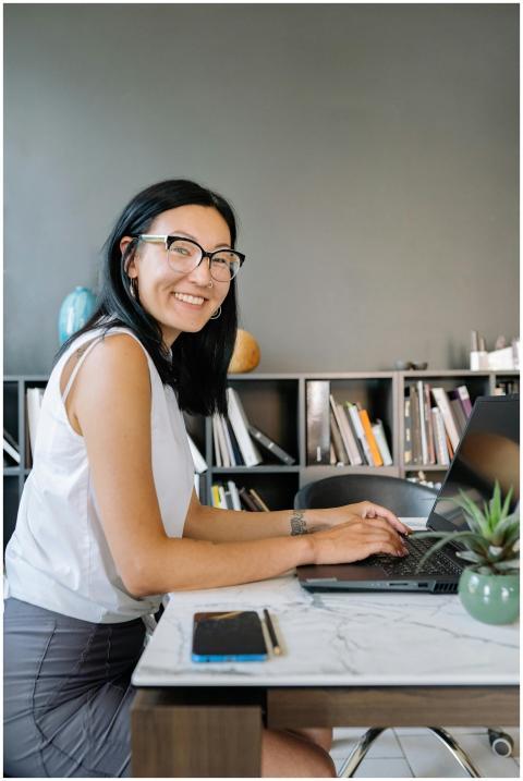 Smiling businesswoman with eyeglasses using laptop