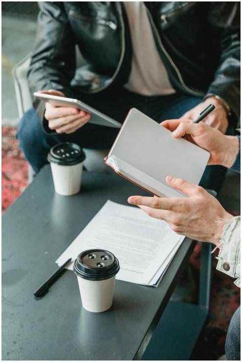 Two businessmen collaborating over notebooks and c