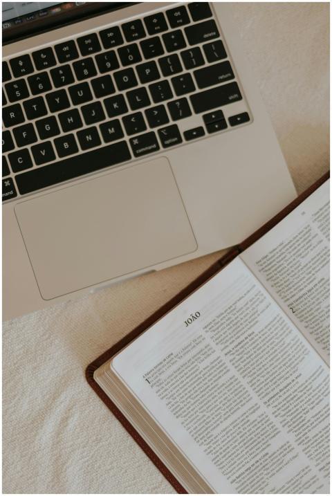 An open Bible beside a laptop, suggesting a blend